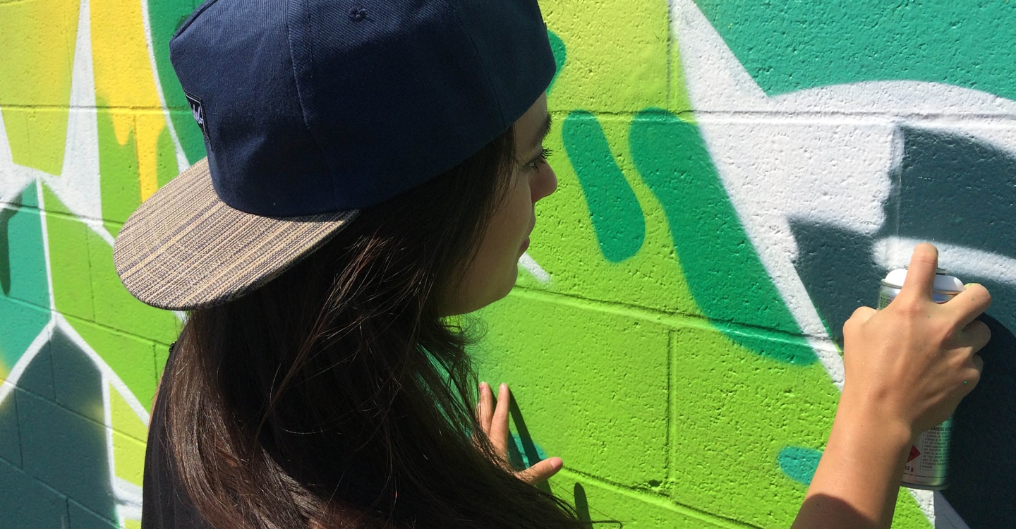 Photograph of a graffiti artist spray painting a wall
