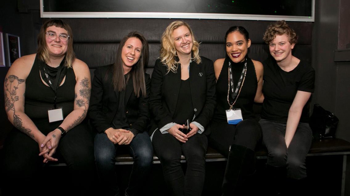 Smiling women sitting on a bench at Lesbians Who Tech Summit.