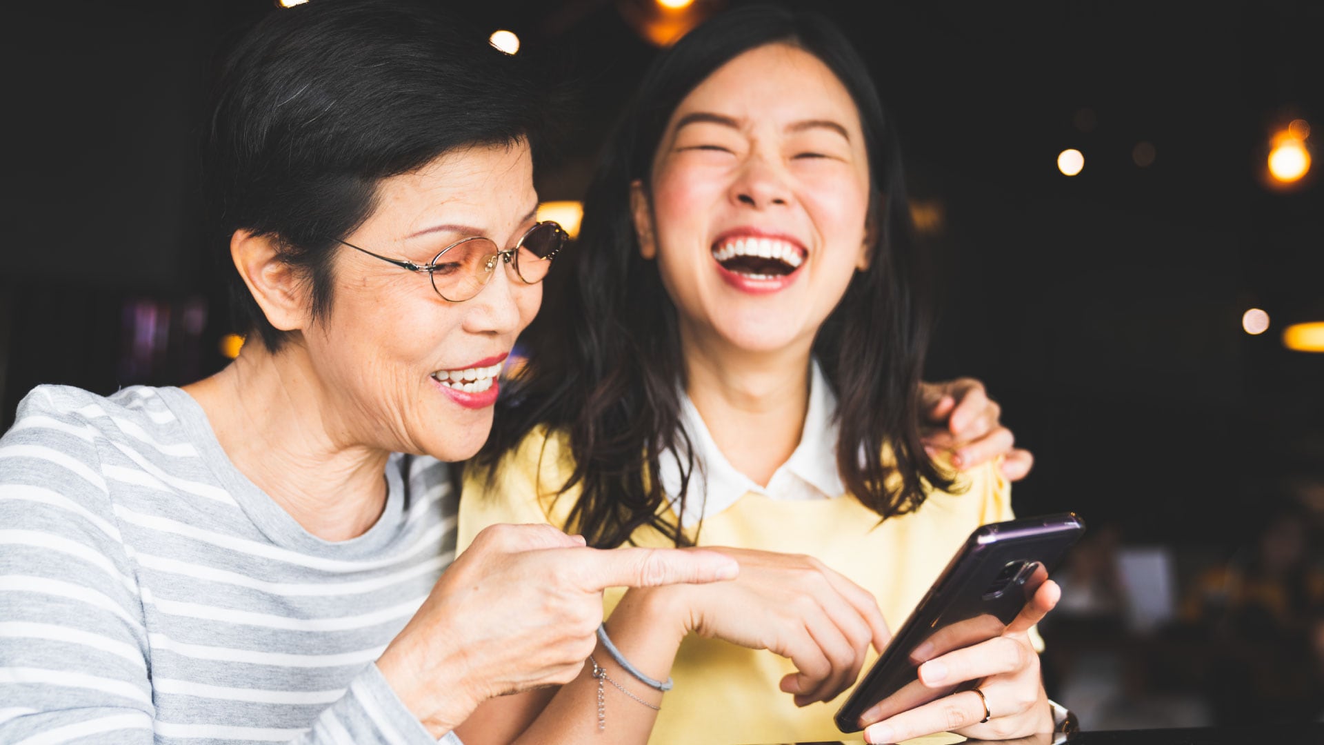 two women using a smart phone and smiling