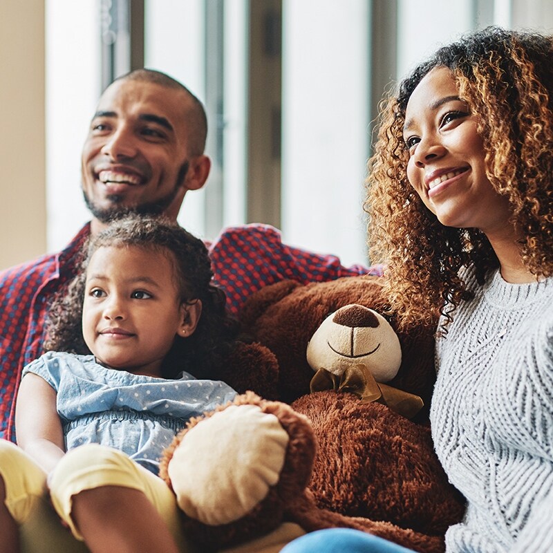 family and teddy bear smiling watching TV