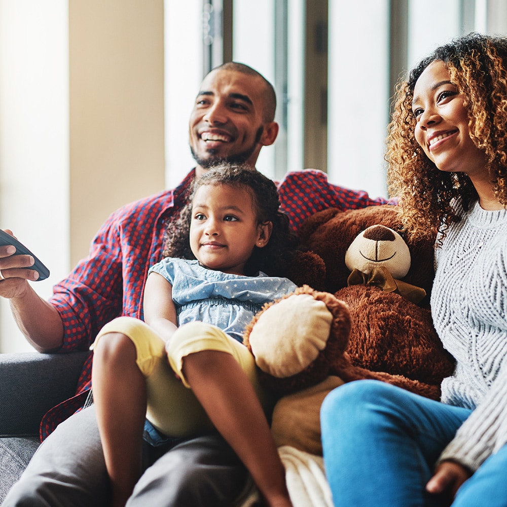 family and teddy bear smiling watching TV